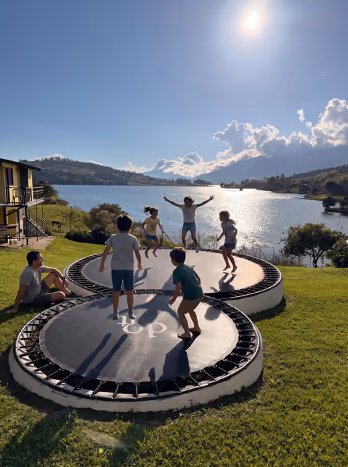 Niños saltando en el brinca brinca frente al lago