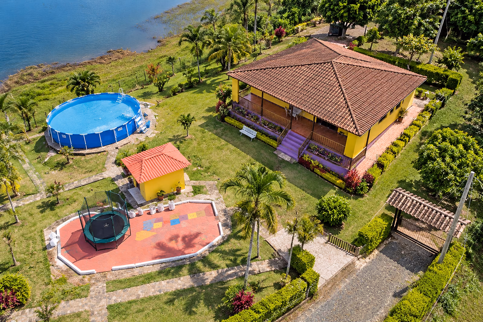 Vista aérea de la finca Tufink: casa de tejas, piscina y zona de juegos frente al Lago Calima